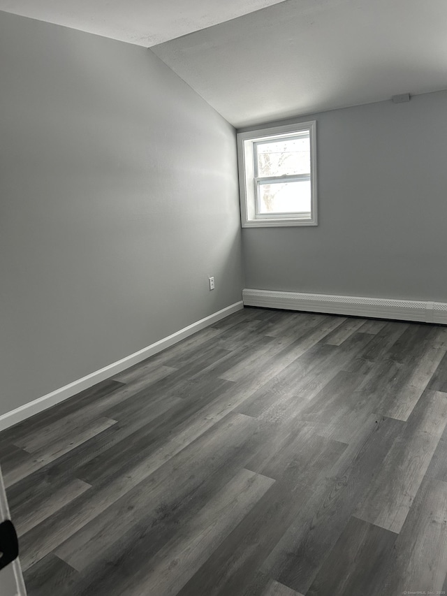 empty room featuring lofted ceiling, baseboards, dark wood finished floors, and baseboard heating