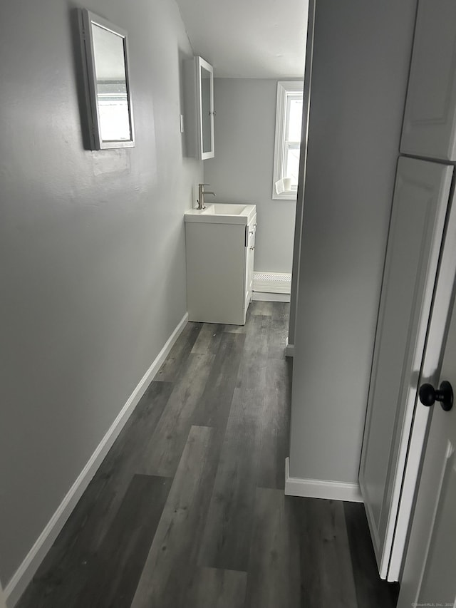 hallway with a wealth of natural light, baseboards, dark wood-style flooring, and a sink