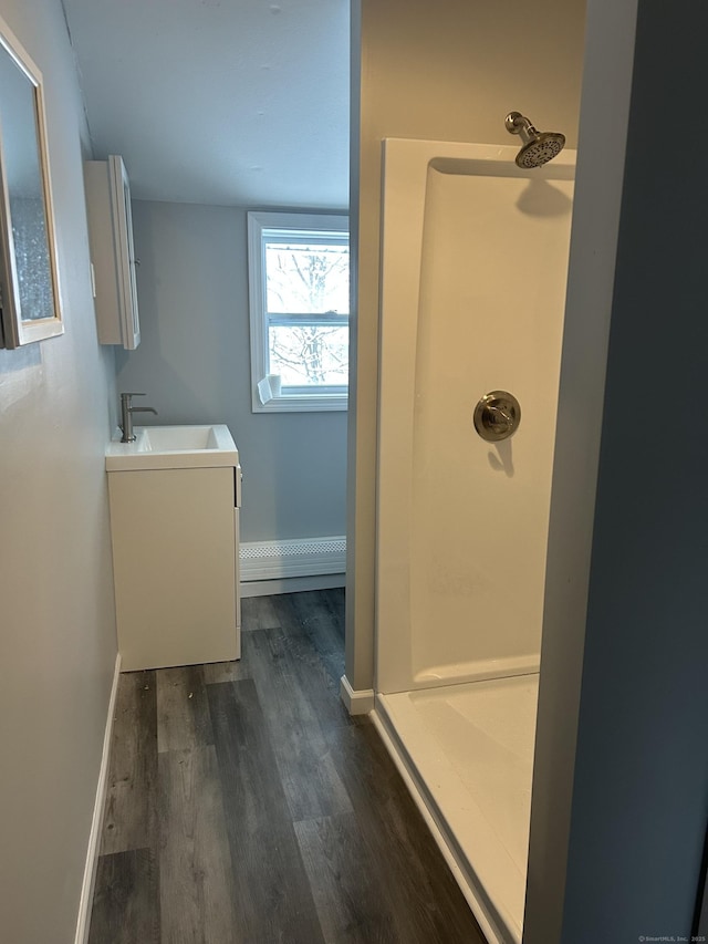 bathroom with a stall shower, vanity, baseboards, and wood finished floors