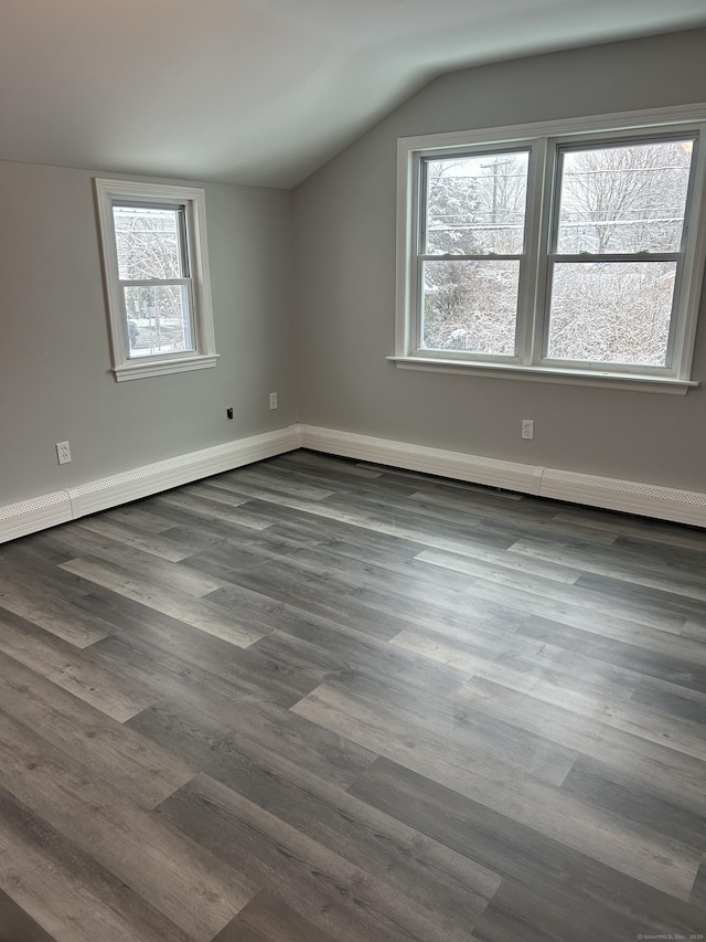 additional living space featuring vaulted ceiling, dark wood-style flooring, and baseboards