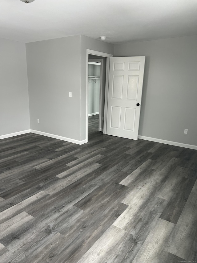 empty room with dark wood-type flooring and baseboards