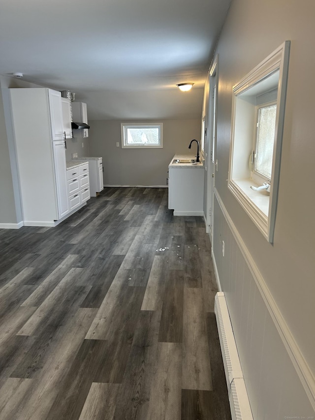 kitchen with white cabinets, dark wood-style floors, a baseboard radiator, light countertops, and a sink