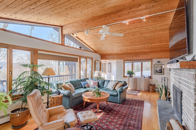 living area with high vaulted ceiling, wood ceiling, a fireplace with raised hearth, and light wood finished floors