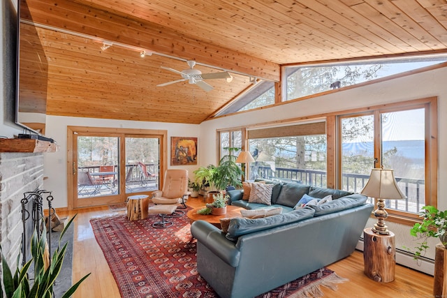 living area with light wood-type flooring, a healthy amount of sunlight, vaulted ceiling with beams, and baseboard heating