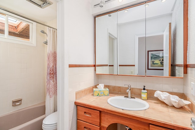 bathroom with toilet, visible vents, vanity, tile walls, and shower / bath combo with shower curtain