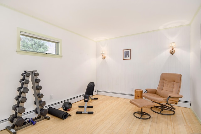 exercise area with a baseboard heating unit, ornamental molding, and wood finished floors