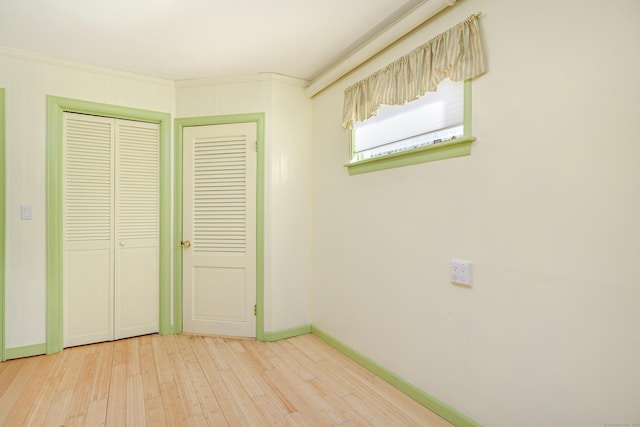 unfurnished bedroom featuring light wood finished floors, baseboards, and a closet