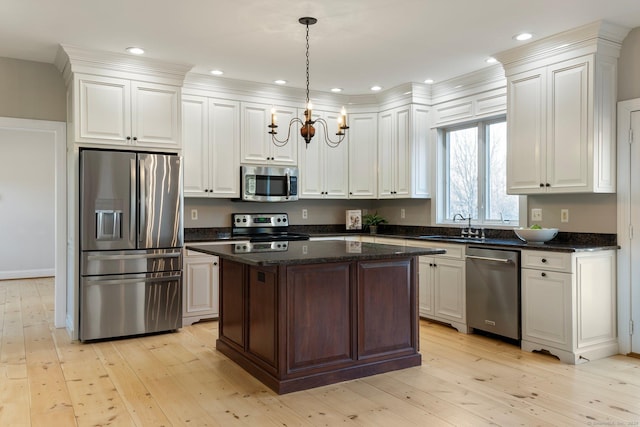 kitchen featuring light wood-style flooring, appliances with stainless steel finishes, a center island, and an inviting chandelier