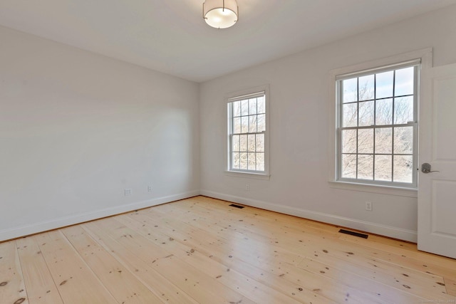 empty room featuring visible vents, baseboards, and wood-type flooring