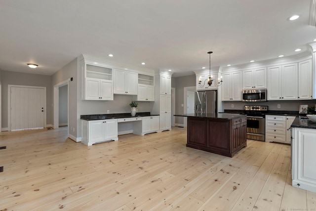 kitchen with a kitchen island, stainless steel appliances, light wood-style floors, an inviting chandelier, and white cabinets