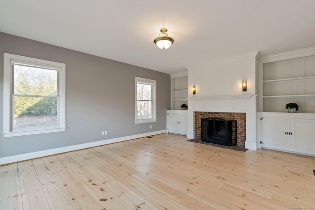 unfurnished living room with baseboards, built in shelves, light wood-style flooring, and a fireplace