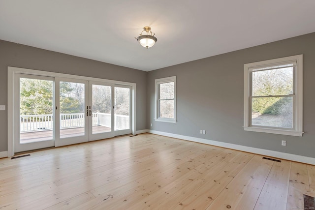 unfurnished room with visible vents, french doors, baseboards, and light wood-style floors