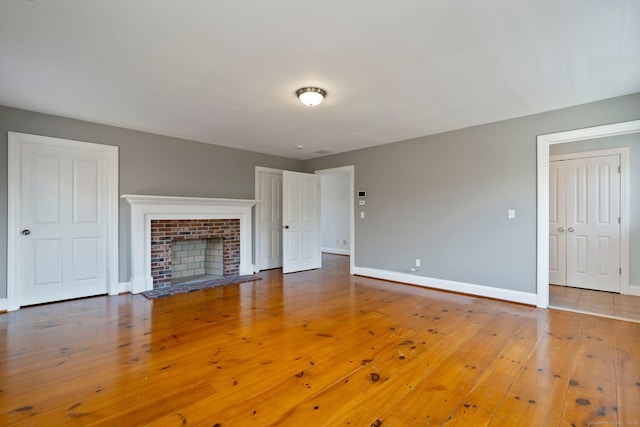 unfurnished living room with baseboards, wood-type flooring, and a fireplace