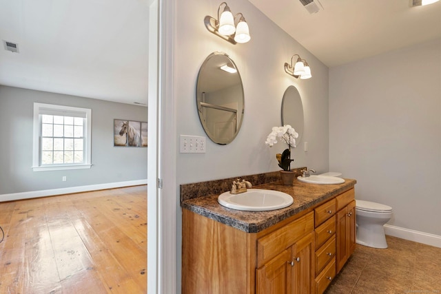 bathroom featuring a sink, visible vents, baseboards, and double vanity