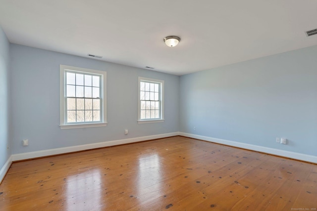 spare room featuring baseboards, wood-type flooring, and visible vents