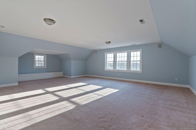 additional living space featuring baseboards, carpet floors, lofted ceiling, and visible vents