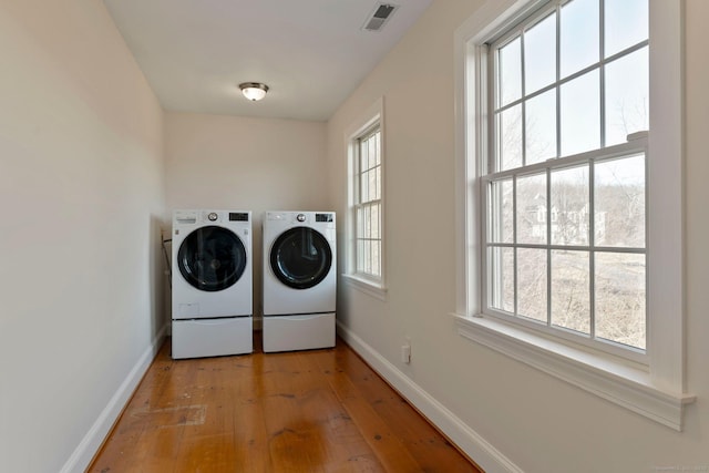 laundry area featuring baseboards, visible vents, light wood finished floors, laundry area, and washer and dryer