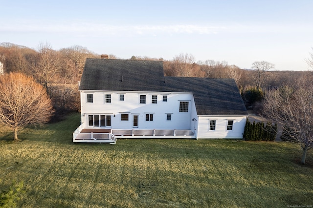 back of property featuring a deck, a lawn, roof with shingles, and a chimney