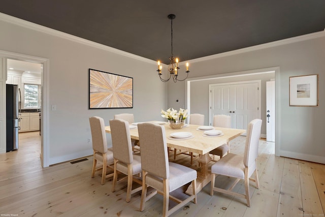 dining space with a chandelier, light wood-style flooring, and crown molding