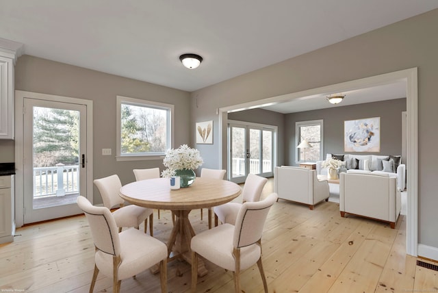 dining room with french doors, a healthy amount of sunlight, and light wood finished floors