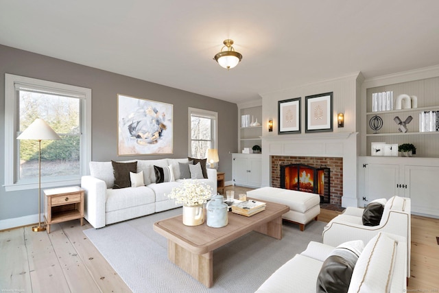 living room with light wood-type flooring, baseboards, built in shelves, and a fireplace