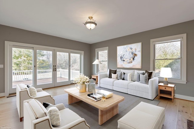 living area with visible vents, light wood-style flooring, french doors, and baseboards