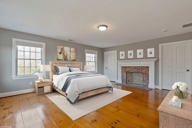 bedroom featuring visible vents, multiple windows, baseboards, and wood-type flooring