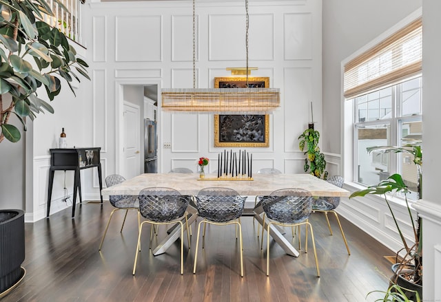 dining area featuring dark wood finished floors, a decorative wall, and a high ceiling