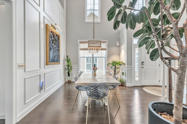 entryway with a wealth of natural light, dark wood-style flooring, a decorative wall, and a towering ceiling