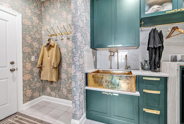 interior space with light tile patterned floors, baseboards, a sink, and wallpapered walls