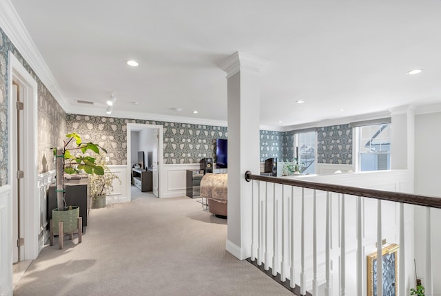 hallway with a wainscoted wall, crown molding, recessed lighting, light colored carpet, and wallpapered walls