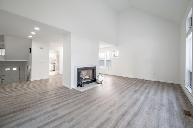 unfurnished living room with light hardwood / wood-style floors and high vaulted ceiling