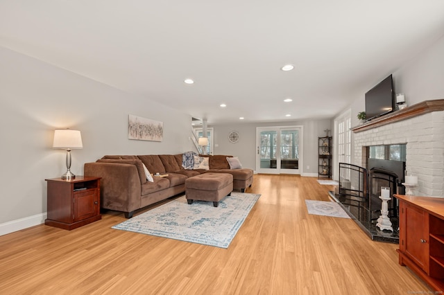 living room featuring a brick fireplace and light wood-type flooring