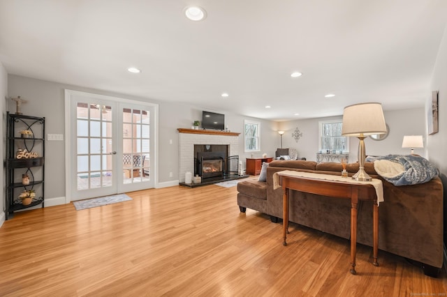 living room with a fireplace, light hardwood / wood-style floors, and french doors