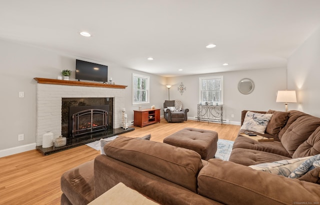 living room featuring hardwood / wood-style flooring, a brick fireplace, and baseboard heating