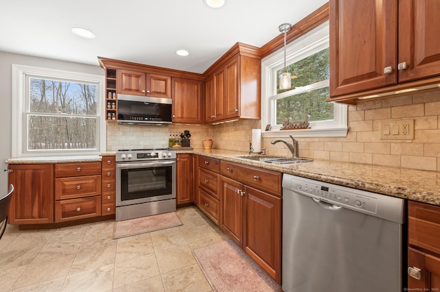 kitchen featuring pendant lighting, sink, decorative backsplash, stainless steel appliances, and light stone countertops