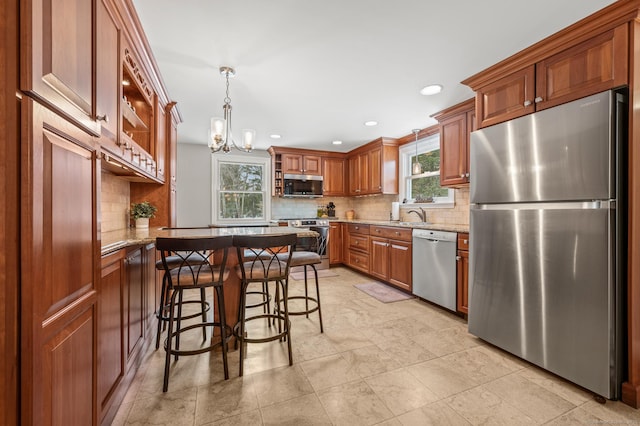 kitchen with decorative light fixtures, light stone countertops, a breakfast bar, and appliances with stainless steel finishes