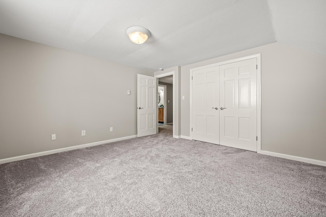 unfurnished bedroom featuring a closet, vaulted ceiling, and carpet