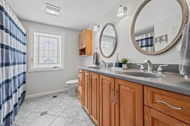 bathroom with tile patterned flooring, vanity, a textured ceiling, and toilet