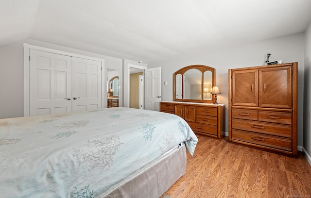 bedroom with lofted ceiling, a closet, and light wood-type flooring