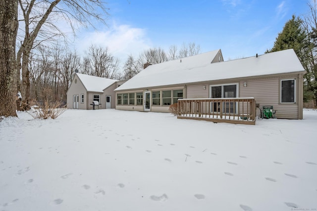 snow covered back of property featuring a wooden deck