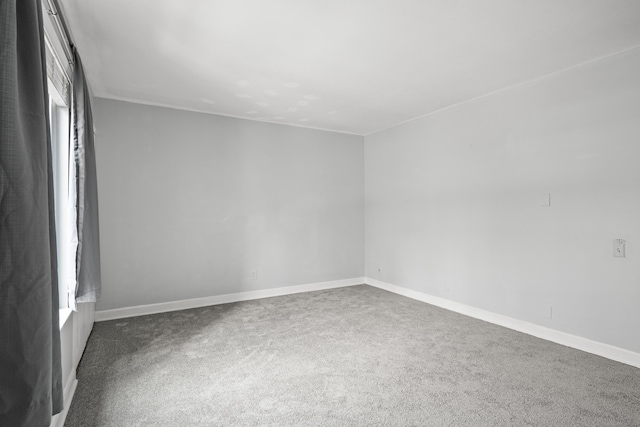 spare room featuring carpet floors and baseboards