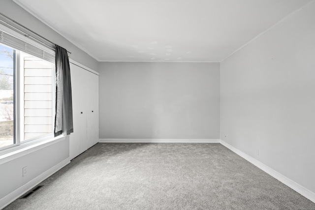 unfurnished room with carpet floors, baseboards, visible vents, and a wealth of natural light