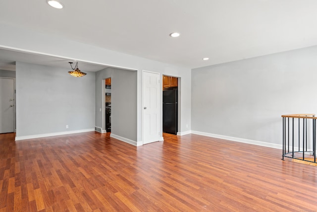 empty room featuring baseboards, wood finished floors, and recessed lighting