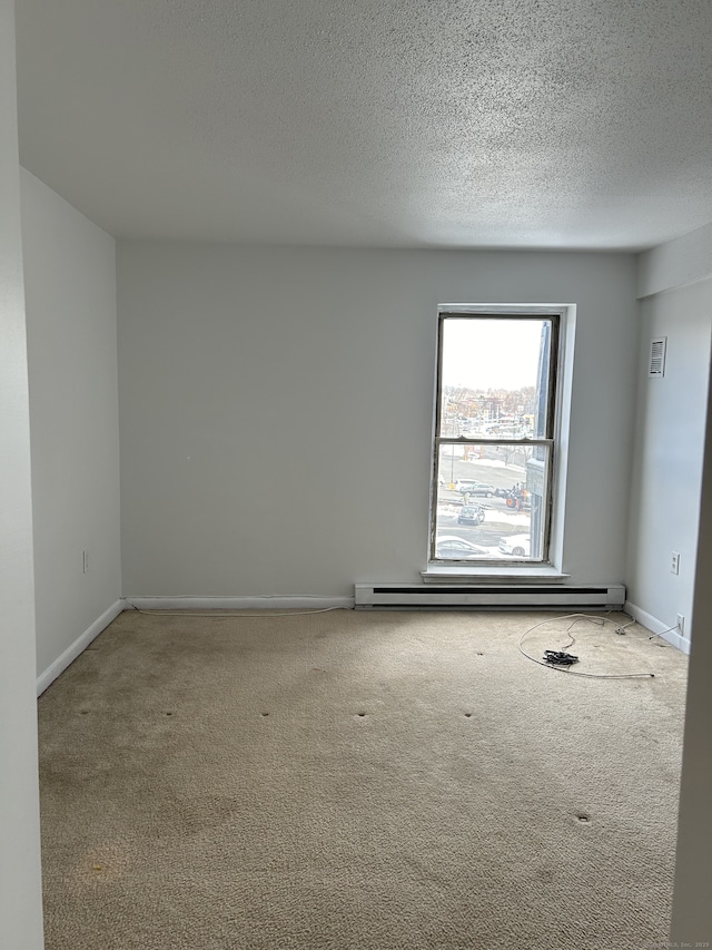 empty room with a baseboard heating unit, a textured ceiling, and carpet flooring