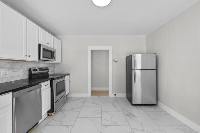 kitchen with ornamental molding, appliances with stainless steel finishes, white cabinets, and backsplash