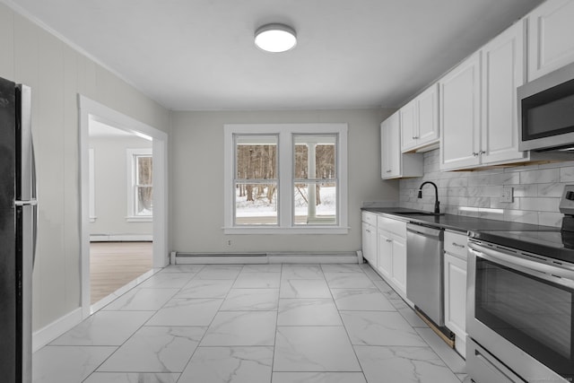 kitchen featuring appliances with stainless steel finishes, white cabinetry, a baseboard radiator, sink, and backsplash