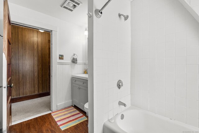 full bathroom featuring hardwood / wood-style flooring, vanity, tiled shower / bath combo, and toilet