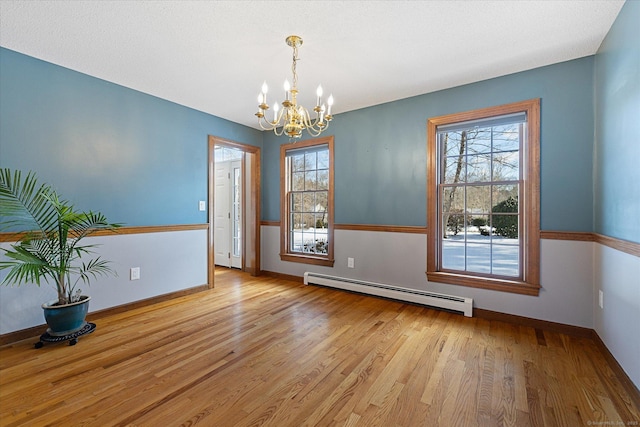 unfurnished dining area featuring a wealth of natural light, light wood-type flooring, a chandelier, and baseboard heating