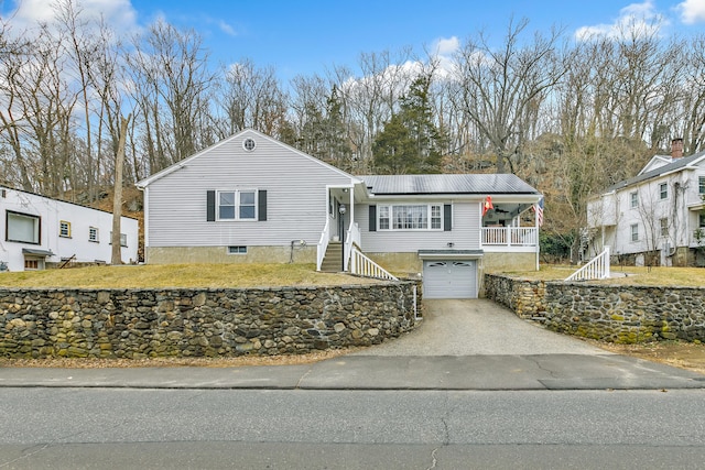 view of front facade with a garage, covered porch, driveway, and a front yard